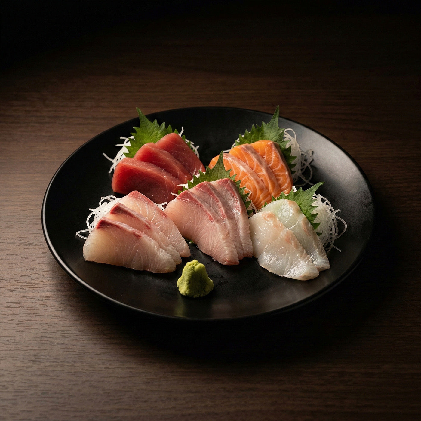黒い皿に盛られた刺身の盛り合わせ。白身、マグロ、サーモン